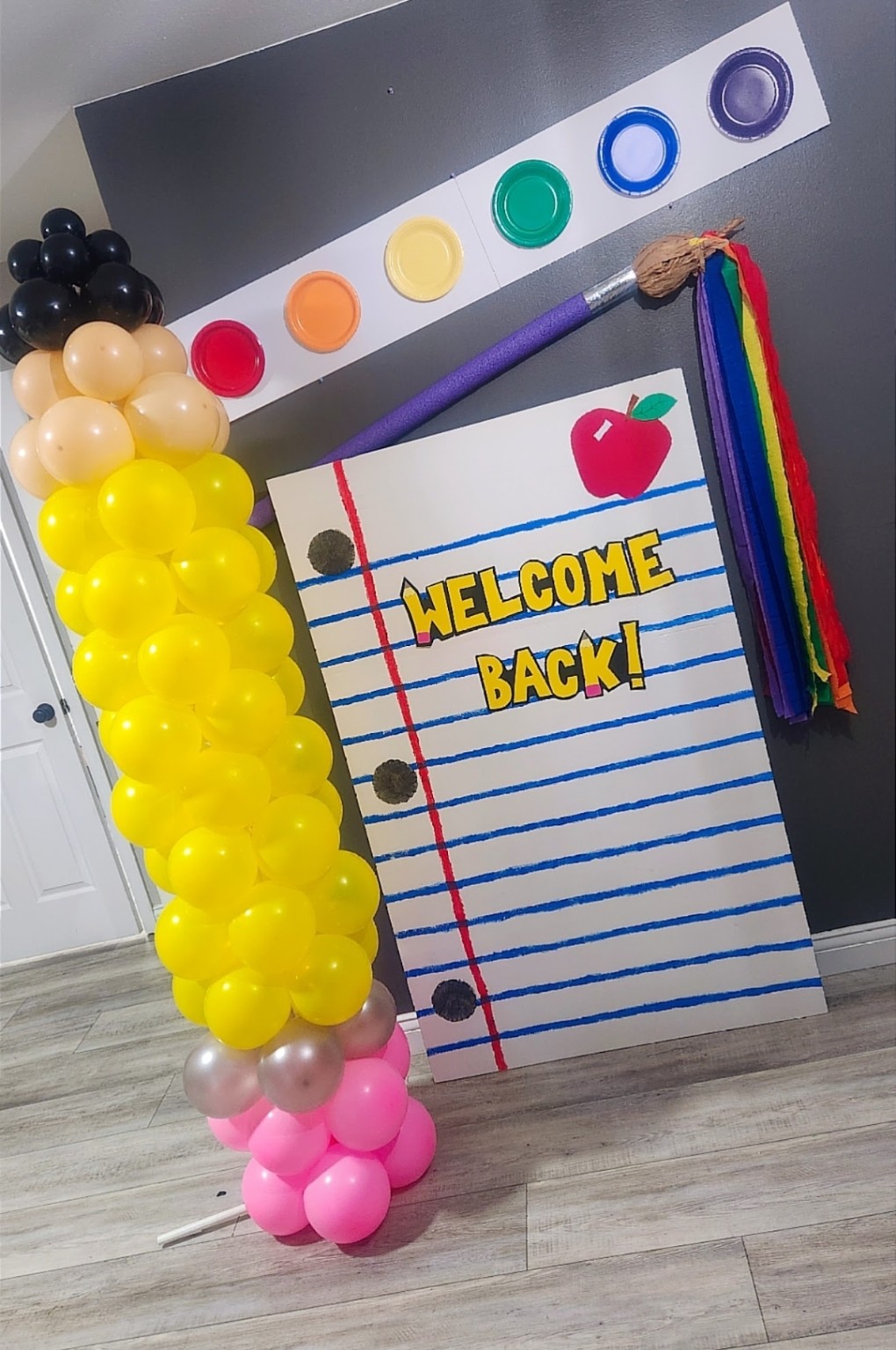 Welcome Back school event display with a giant pencil, notebook backdrop and yellow balloon column